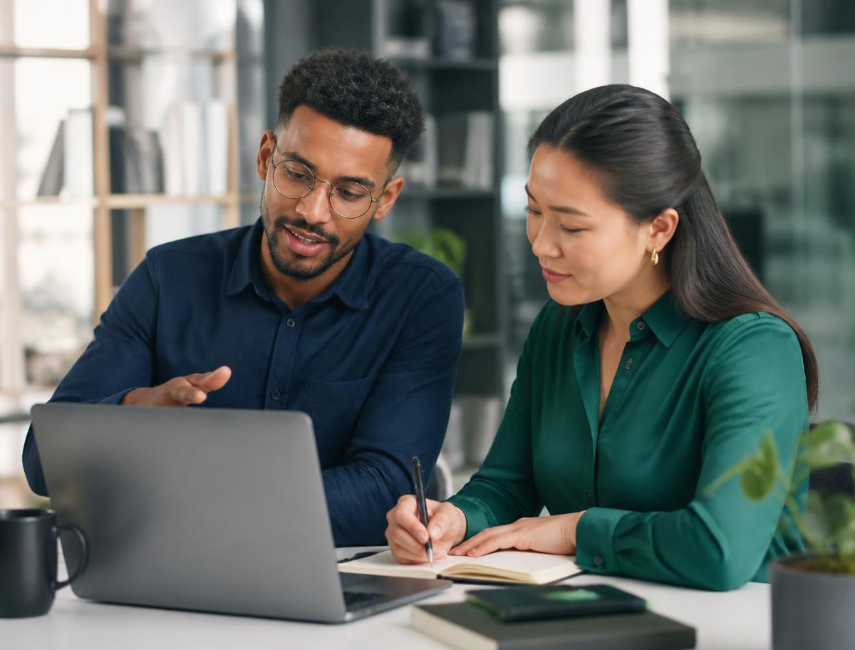 Two professionals collaborating over a laptop in a modern office