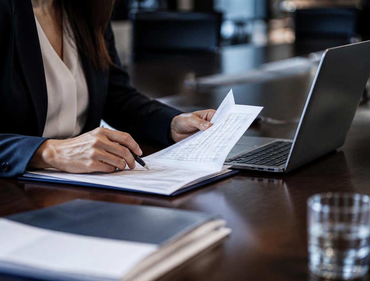 Auditor examining printed training records alongside a laptop